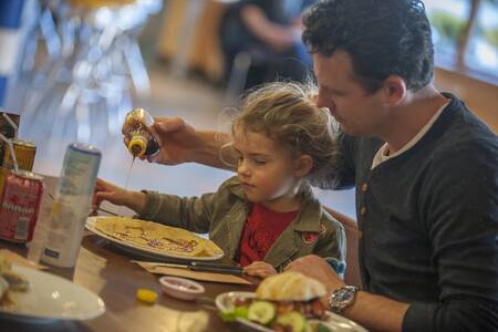 Familie isst Pfannkuchen in einem Restaurant im Roompot Ferienpark Aquadelta