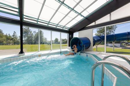 Junge auf der großen Rutsche im Hallenbad des Roompot Ferienpark Callassande