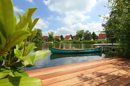 Blick von einer Terrasse auf dem Wasser auf ein Ferienhaus im Roompot Ferienpark Emslandermeer