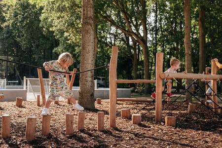 Kinder auf hölzernen Spielgeräten auf einem Spielplatz im Roompot Vakantiepark Kijkduin