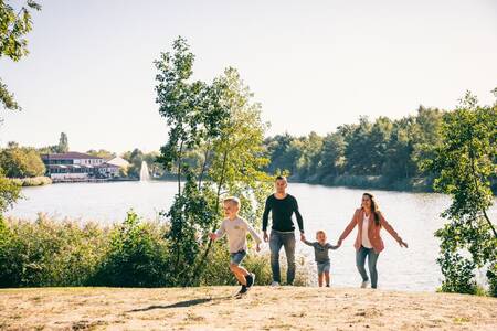 Eine Familie geht am Strand des Freizeitsees im Roompot Vakantiepark Weerterbergen spazieren