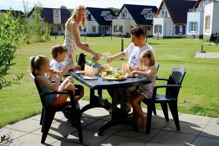 Familie isst auf der Terrasse eines Ferienhauses im Roompot Ferienresort Cochem