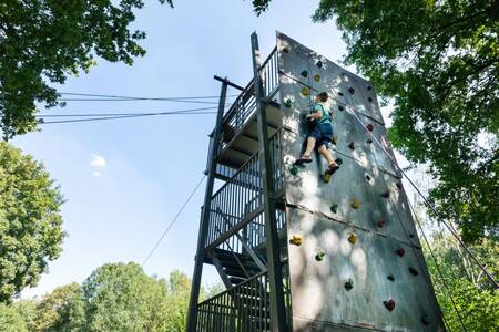 Junge klettert auf den Kletterturm des Ferienparks Roompot Hunzepark