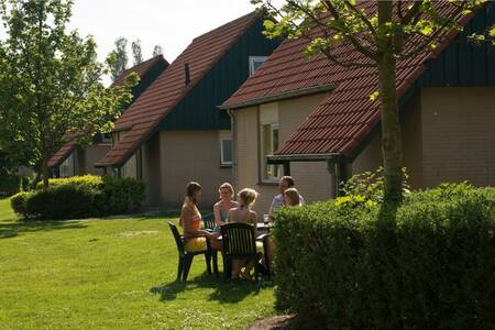 Menschen sitzen im Garten eines Ferienhauses im Ferienpark Roompot Kustpark Klein Poelland