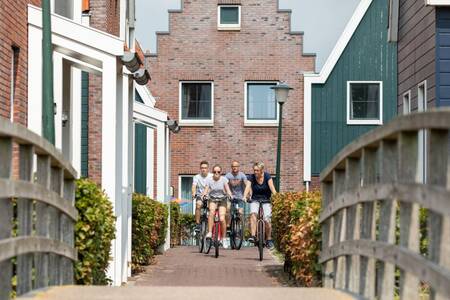 Die Familie radelt zwischen den Ferienhäusern zu einer Brücke im Roompot Marinapark Volendam