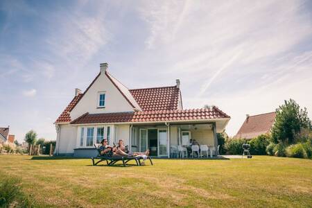 2 Personen im Garten eines freistehenden Ferienhauses in der Roompot Noordzee Résidence Cadzand-Bad