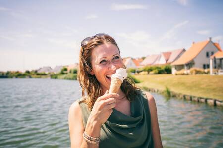Frau isst ein Eis vor den Ferienhäusern der Roompot Noordzee Résidence Cadzand-Bad