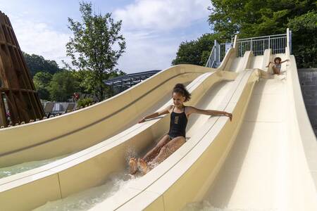 Kinder rutschen die große Rutsche im Pool des Ferienparks Roompot Parc la Clusure hinunter