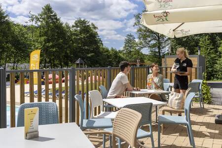 Paar auf der Terrasse am Swimmingpool im Ferienpark Roompot Parc la Clusure