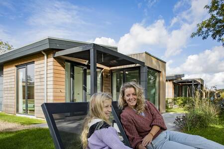 Menschen auf Liegestühlen im Garten eines Ferienhauses im Ferienpark Roompot Park Wijdenes