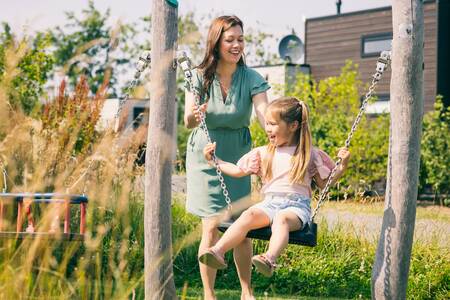 Mutter und Tochter auf der Schaukel auf dem Spielplatz im Ferienpark Roompot Park Zeedijk