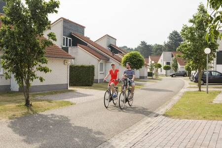 Eine Familie radelt zwischen den Ferienhäusern im Ferienpark Roompot Resort Arcen hin und her