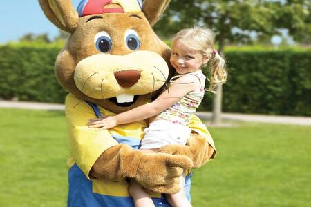 Mädchen wird von Koos-Kaninchen im Ferienpark Roompot De Katjeskelder hochgehoben