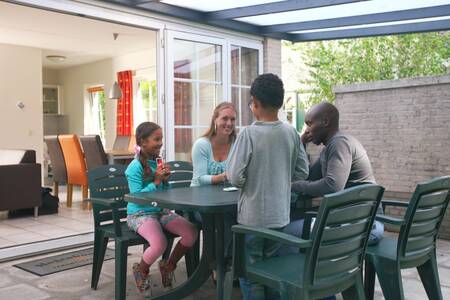 Familie am Tisch unter einem Dach in einem Ferienhaus im Roompot Ferienpark Hellendoorn