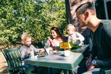 Familie am Tisch im Garten eines Ferienhauses im Roompot Vakantiepark Weerterbergen