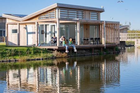 Menschen auf der Terrasse direkt am Wasser eines Ferienhauses im Ferienpark Roompot Water Village