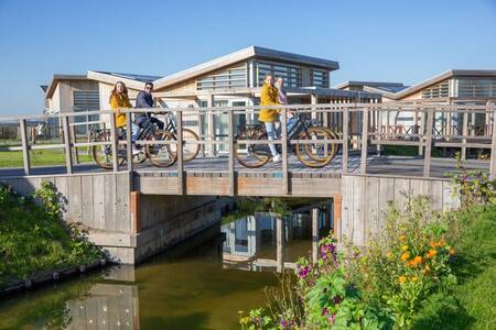 Menschen auf einer Brücke und Ferienhäuser im Ferienpark Roompot Water Village