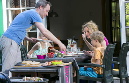 Die Familie isst im Garten eines Ferienhauses im Ferienpark Roompot Zeebad