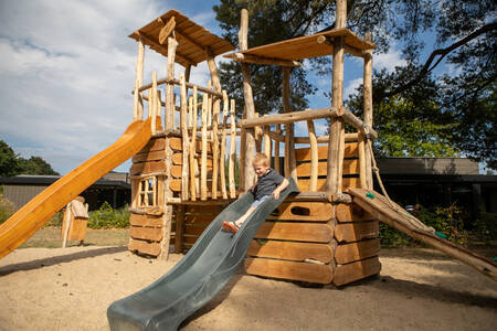 Kleiner Junge auf der Rutsche auf dem Spielplatz im Ferienpark Soof Retreats Soof Heuvelrug