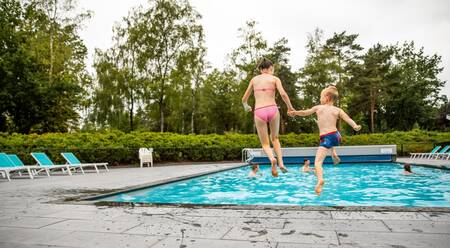 Zwei Kinder springen in den Außenpool des Topparken Recreatiepark 't Gelloo