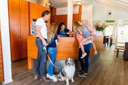 Familie mit Hund an der Rezeption des Ferienparks Topparken Parc de IJsselhoeve