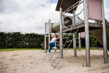 Kind klettert auf einem Spielplatz auf einem Spielplatz im Ferienpark Topparken Park Westerkogge