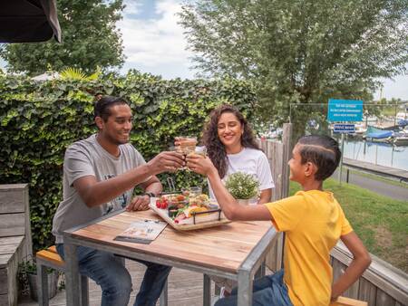 Familie beim Essen auf der Terrasse des Restaurants im Topparken Recreatiepark het Esmeer