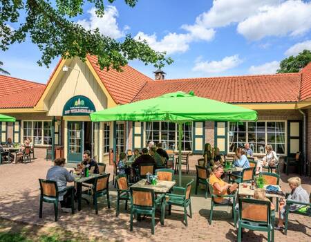 Menschen sitzen auf der Terrasse des Restaurants des Ferienparks Topparken Resort Veluwe