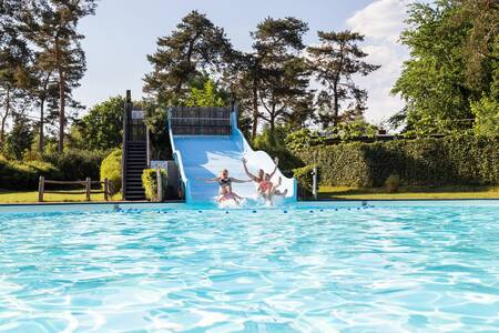 Kinder rutschen die breite Rutsche im Außenpool des Ferienparks Topparken Resort Veluwe hinunter