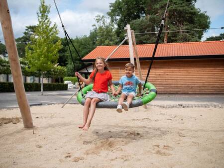 Kinder auf einer Schaukel auf dem Spielplatz des Ferienparks Topparken Resort Veluwe