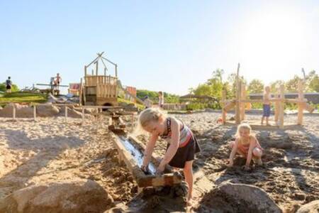 Auf dem Spielplatz des Ferienparks Ackersate spielen Kinder mit Wasser und Sand