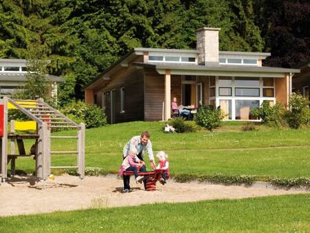 Vater mit 2 Kindern auf dem Spielplatz im Ferienpark Landal Village l'Eau d'Heure